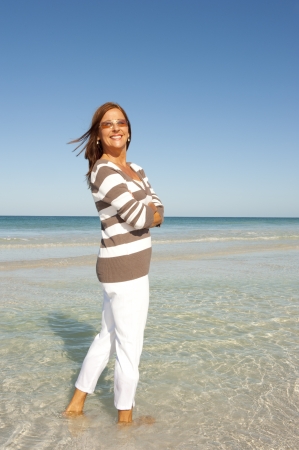 Portrait Active and attractive middle aged woman enjoying happy retirement with holiday at beach, isolated with ocean and sky as background and copy space.の写真素材