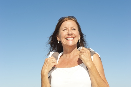 Portrait Active and attractive middle aged woman enjoying happy retirement with summer sunny holiday, isolated with blue sky as background and copy space.の写真素材