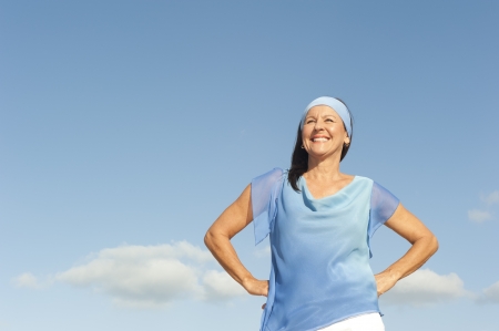 Portrait successful beautiful looking middle aged woman confident, happy and relaxed smiling, enjoying active retirement, isolated with blue sky as background and copy space.の写真素材