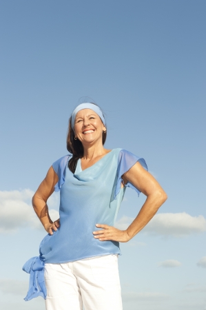 Portrait successful beautiful looking middle aged woman confident, happy and relaxed smiling, enjoying active retirement, isolated with blue sky as background and copy space.の写真素材