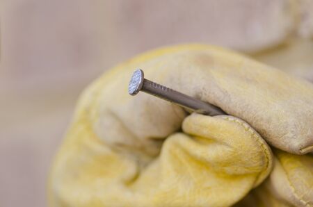 Closeup of hand in gloves with nail and and brick wall as blurred background plus copy space の写真素材