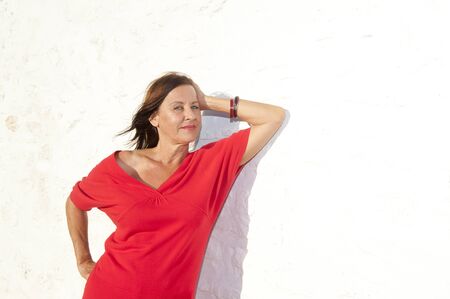 Portrait Sexy mature woman wearing red standing relaxed sunny day outdoor,  isolated on white wall background.の写真素材