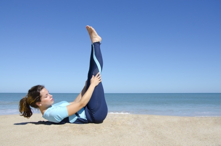 Attractive fit and healthy young woman doing gymnastic or yoga exercising at tropical beach, isolated with ocean and blue sky as background and copy space.の写真素材