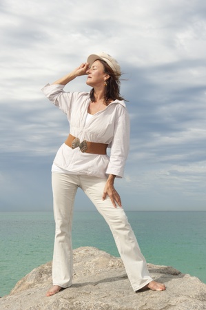 Portrait attractive mature woman dressed in white and standing in relaxed and confident poseの写真素材