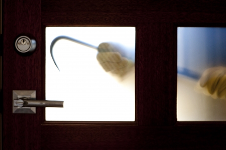 Hands of Burglar, thief  with gloves, holding crowbar trying to break in home, unlock door, blurred visible silhouette behind milky windows, with copy space.の写真素材