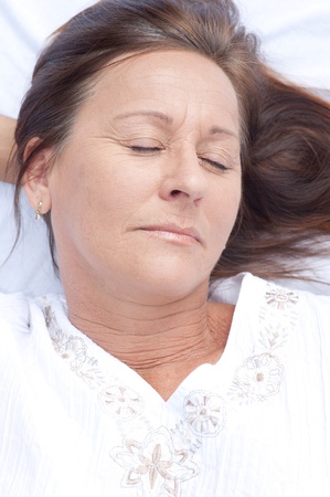 Portrait relaxed attractive mature woman lying asleep in bed with closed eyes and smile on face, peaceful, happy expression, enjoying leisure lifestyle.の写真素材