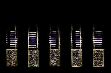 Modern designer lamps illuminated isolated on black background with symmetric stripes shiny bubbles...
