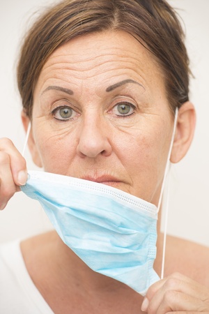 Portrait mature woman nurse or doctor, medical professional with mask and serious facial expression isolated on white background.の写真素材