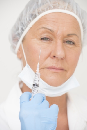 Portrait serious professional female hospital nurse in blurred background with syringe, vaccine injection, isolated on white の写真素材