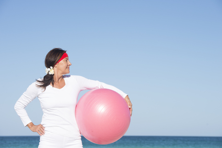 Sporty attractive mature woman confident at beach with gymnastic ballの写真素材