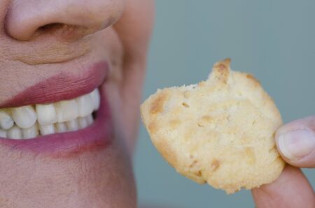 Close up portrait of female smiling mouth and teeth eating cookie as sweet snack, dental care.の写真素材