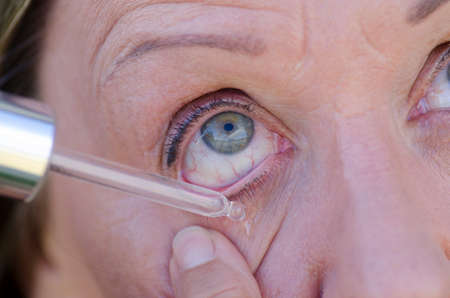Close up image of female human eye with pipette dropping helping liquid medicine.の写真素材