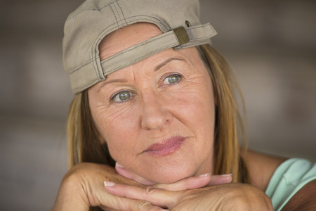 Portrait attractive fit active mature woman wearing green sporty top and cap, thoughtful relaxed,...