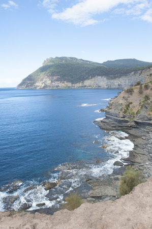 High steep coast on Maria Island, Tasmania, Australia, National Park and World Heritage Site, with wild ocean and mountain of Bishop and Clerk as background, copy space.の写真素材