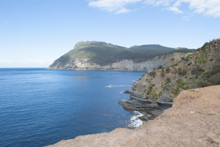 Steep cliff coast on Maria Island, Tasmania, Australia, National Park and World Heritage Site, with ocean and mountain of Bishop and Clerk as background, copy space.の写真素材