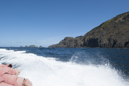 Sailing tour along steep high cliff coast of Bruny Island, Tasmania, with view over remote wild Southern Ocean to horizon, blue sky and copy space.の写真素材