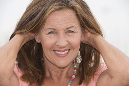 Portrait attractive mature woman posing happy smiling with hands behind head, relaxed enjoying...