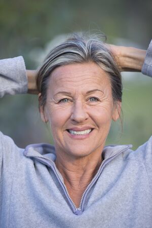 Portrait attractive mature woman outdoor, happy relaxed with hands behind neck