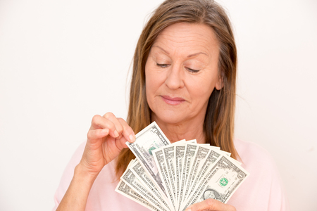 Portrait happy attractive mature woman presenting US dollar notes, isolated, bright background.の写真素材