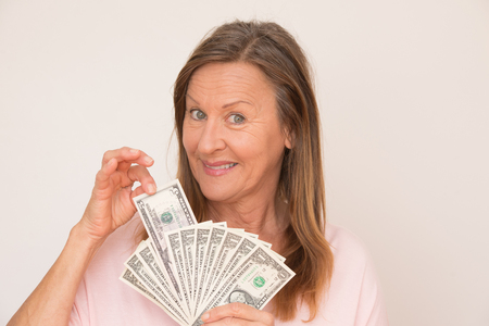 Portrait happy attractive mature woman presenting US dollar currency, isolated, bright background.の写真素材