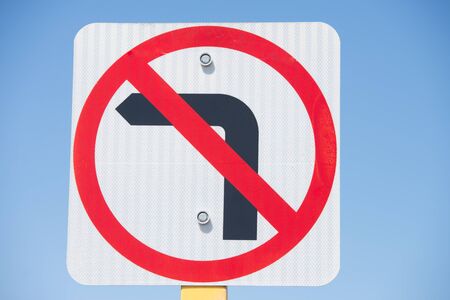 Traffic Street sign left turn prohibited, arrow crossed with red line, blue sky as background.の写真素材