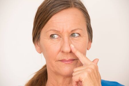 Portrait smart attractive mature woman with idea, finger at nose, happy look, isolated, bright background.の写真素材