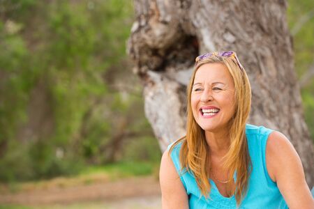 Portrait attractive relaxed senior woman with joyful happy friendly smile sitting in park, blurred outdoor background, copy space.の写真素材