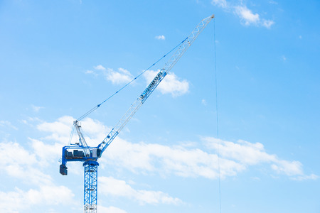 Tall crane on construction site against blue sky background, copy space.の写真素材