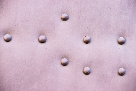 Vintage metal plate, painted brown, with eight metal rivets in it. Industrial or architectural abstractの写真素材