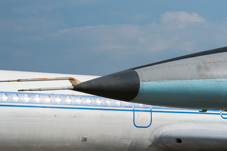 Nose of a military aircraft against the background of a fuselage or body of a vintage civil passenger plane or airliner.の写真素材