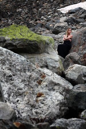 blond woman in black dress among the huge stones on the glacier. Mestia, Georgiaの写真素材