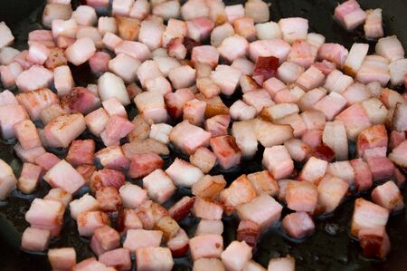 Frying chopped bacon on black pan.の写真素材