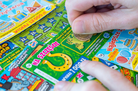Pruszcz Gdanski, Poland - December 1, 2017: Man hand scratching a Polish lottery lottery scratch card with a coin on wooden table.のeditorial素材