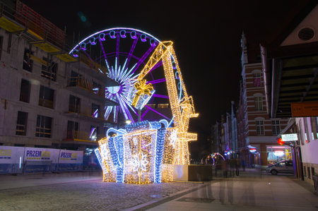 Gdansk, Poland - December 9, 2017: Gifts and crane as christmas decorations with ferris wheel in background.のeditorial素材