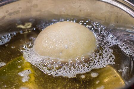 Frying packages in metal pot. Packages are Polish donuts.の写真素材
