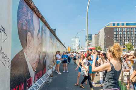 Berlin, Germany - August 16, 2018: People taking pictures of Berlin wall with graffiti painting known as My God, Help Me to Survive This Deadly Love.のeditorial素材
