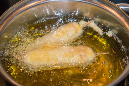 Deep frying corn dogs in oil. Sausage on a stick that has been coated in a thick layer of cornmeal batter.の写真素材