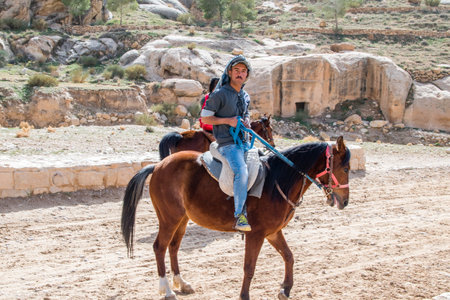 Petra, Jordan - February 8, 2019: Man on horses on road to Rose City knows also as Petra. Petra is one of the New Seven Wonders of the World.のeditorial素材