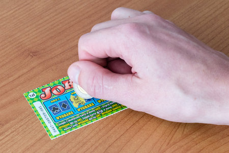 Pruszcz Gdanski, Poland - March 8, 2019: Scratching a scratch-off Lotto lottery ticket.のeditorial素材