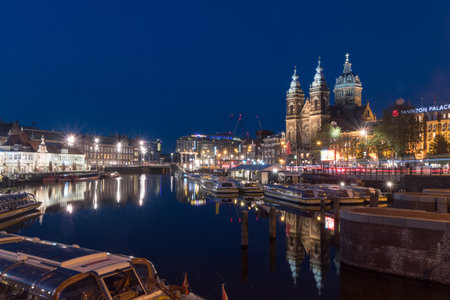 Amsterdam, Netherlands - June 6, 2019: Amsterdam canal with Basilica of Saint Nicholas at dusk.のeditorial素材