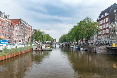 Amsterdam, Netherlands - June 6, 2019: View of Amsterdam's canal with small bouts at cloudy day.のeditorial素材
