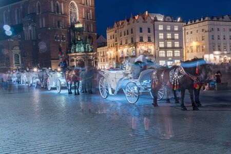 Horse carriages at Main Square in Krakow at night, Poland.の写真素材