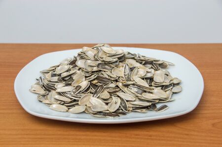 Many empty shells of sunflower seeds on white plate.の写真素材