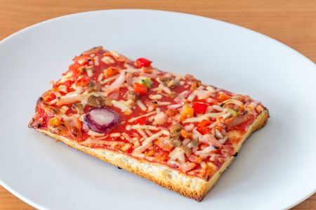 Baked cheap frozen pizza on a white plate.の写真素材