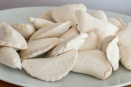 Raw frozen uncooked dumplings on white plate.の写真素材