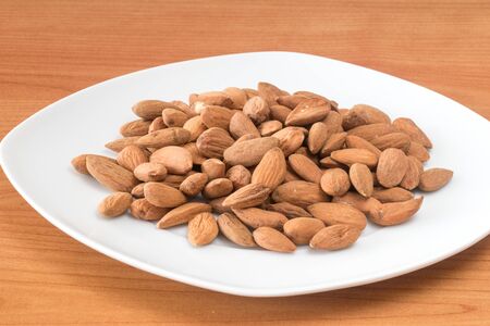 Almonds on white plate on table. Delicious and healthy protein-rich diet food.の写真素材