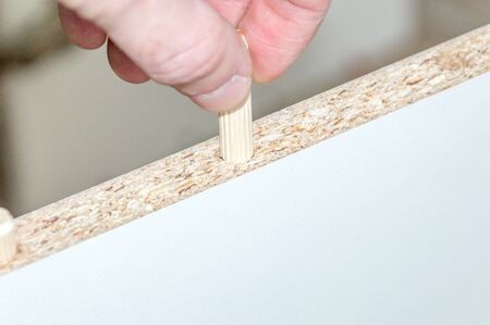 Inserting a wooden dowel into the hole in board chipboard.の写真素材