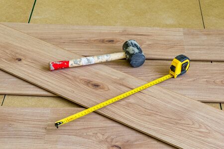 Metal measuring tape and rubber hammer on floor panels when laying them on the floor.の写真素材
