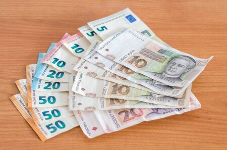 Euro (EUR) and Croatian kuna banknotes (HRK) on wooden table.の写真素材