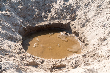 Water in a hole in the sand at the beach.の写真素材